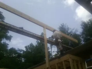Carpenter setting a ridge beam over a new addition frame — Ice Dam Removal by Roofing Brothers in Martin