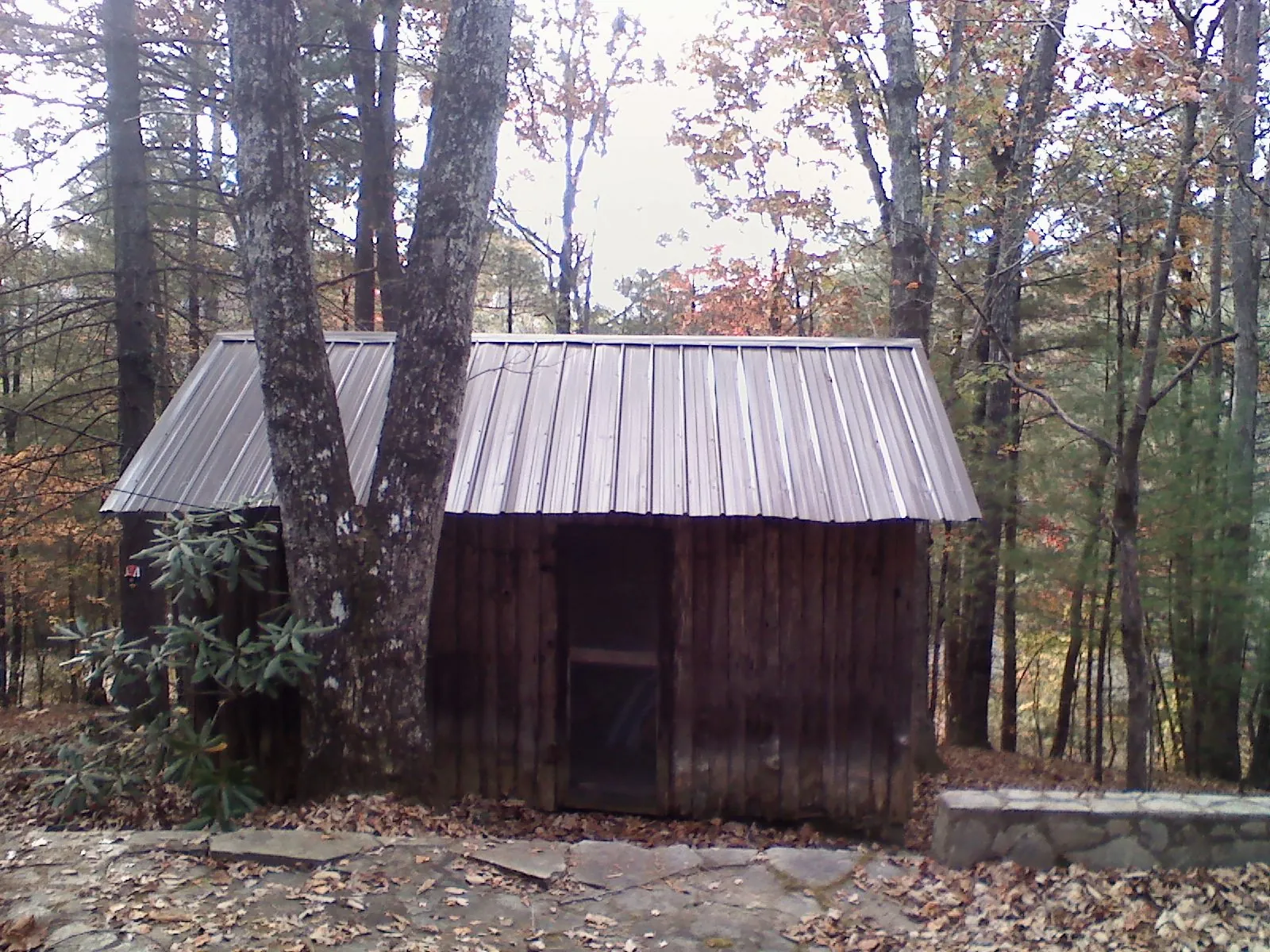 New metal gable roof on a small log shed among the trees in Martin
