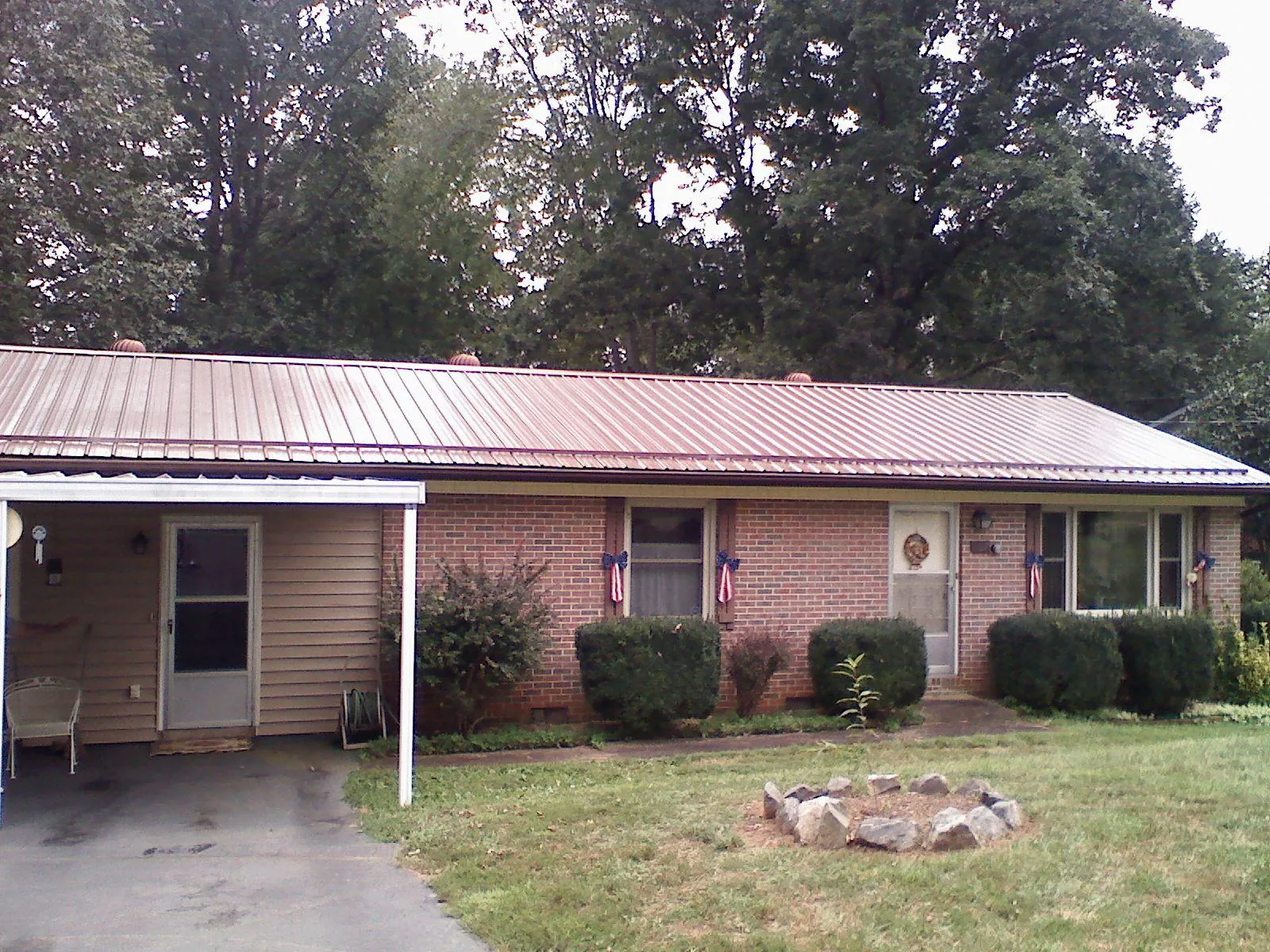Bronze metal roof and carport on a brick ranch home — Roof Repair work by our crew in Martin